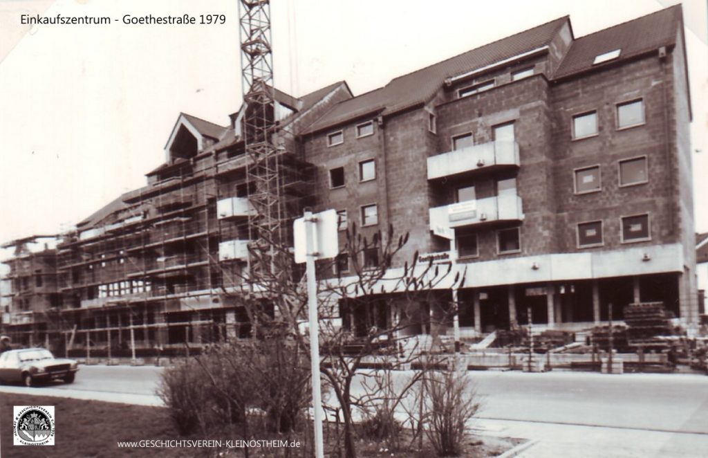 Nachdem der östliche Teil der Goethestraße zwischen Kirchstraße und Josef-Hepp-Straße schon eine Zeitlang mit Wohnblocks bebaut worden war, wurde 1979 die westliche Seite in Angriff genommen. Es sollten Wohnungen und eine Ladenzeile mit Geschäften und Gaststätten entstehen, eine Art „Mini-City-Galerie“ (Zitat aus dem Aschaffenburger Volksblatt). Geplant war hier eine Art Ortszentrum für Kleinostheim.