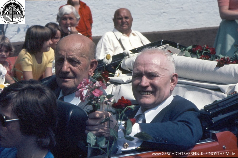 Das Foto stammt vom Festzug bei der 1000-Jahr-Feier der Gemeinde Kleinostheim im Jahre 1975. Zu sehen ist links Altbürgermeister Karl Wienand, rechts der Unternehmer Karl Wienand II.