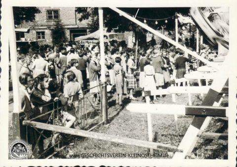 Das Foto stammt vom Heimatfest 1956.Die Menschen stehen vor der Schiffschaukel, die auf dem Platz vor der Turnhalle aufgebaut wurde.