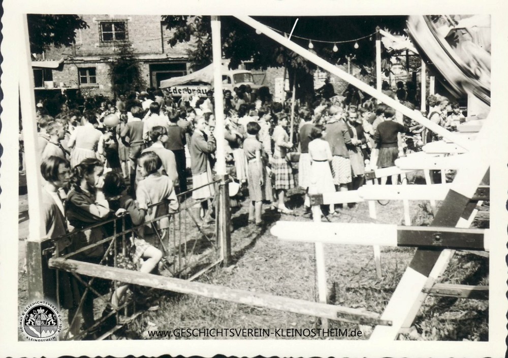 Das Foto stammt vom Heimatfest 1956.Die Menschen stehen vor der Schiffschaukel, die auf dem Platz vor der Turnhalle aufgebaut wurde.