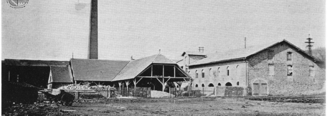 Das Foto zeigt die Tonwarenfabrik Geiger & Goller in der Nähe des Bahnhofs. Sie wurde 1884 gegründet und fertigte Ziegelsteine (Blendsteine). 1936 wurde sie verkauft und nach Mainflingen verlegt. Nachdem im Krieg hier russische Kriegsgefangene untergebracht waren, ließ die Gemeinde das Gebäude renovieren, in dem sich dann ab 1950 die Strumpffabrik Lasea niederließ.