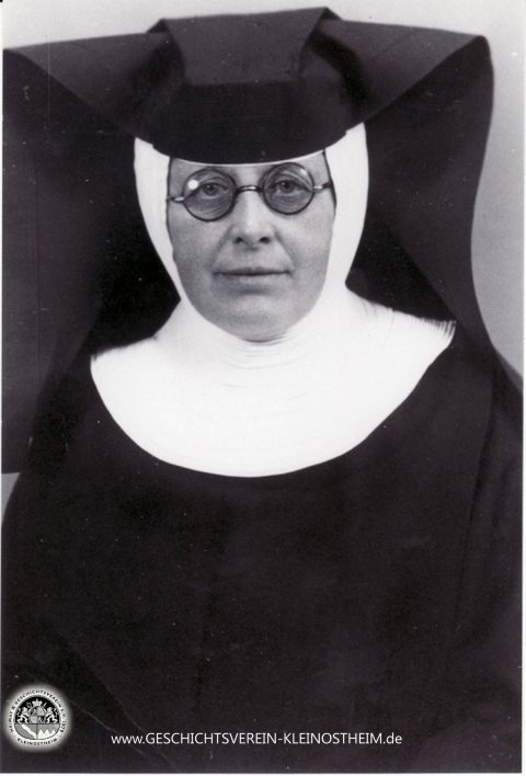 Das Foto zeigt Schwester Barbara Fries (1886 – 1951). Sie war Krankenschwester der Dillinger Franziskanerinnen und zwischen 1922 und 1951 in der ambulanten Krankenpflege in Kleinostheim tätig. Für ihre Leistungen wurde sie 1951 zur Ehrenbürgerin ernannt. Die Barbarastraße erinnert noch heute an sie.