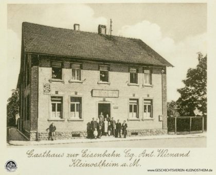 Das Foto aus dem Jahr 1940 zeigt das Gasthaus zur Eisenbahn, ab ca. 1968 auch bekannt unter dem Namen Cille-August. Gegründet wurde es 1906 von Cäcilie und Georg Wienand. Später bekam es den Namen „Kleinostheimer Hof“. 2020 wurde es geschlossen.