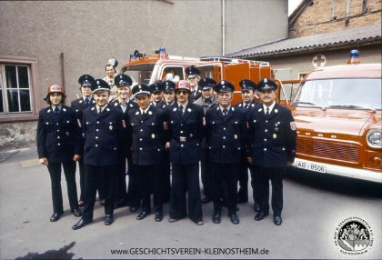 Das Foto zeigt die Feuerwehr in den 1970er Jahren im oben erwähnten Schulhof. Im Hintergrund sieht man das Sanitätsheim mit dem Roten Kreuz.Das Foto zeigt die Feuerwehr in den 1970er Jahren im oben erwähnten Schulhof. Im Hintergrund sieht man das Sanitätsheim mit dem Roten Kreuz.